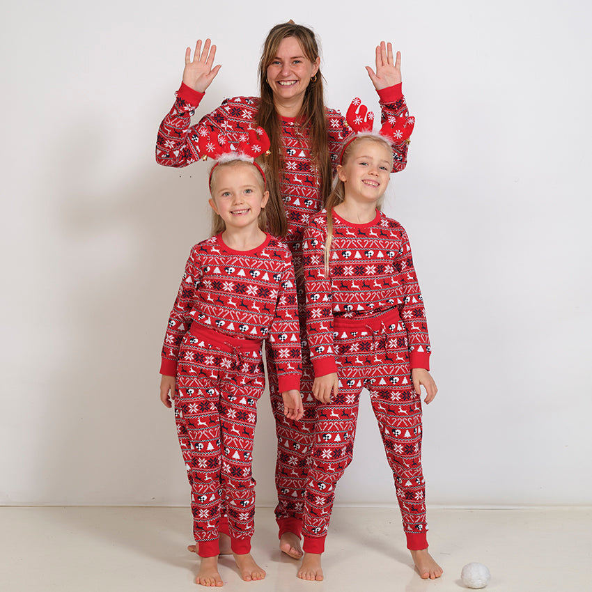 En dame og to børn iført hver deres røde pyjamas i juletema.